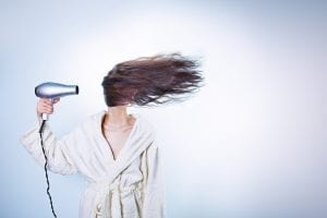 woman blow drying hair in robe